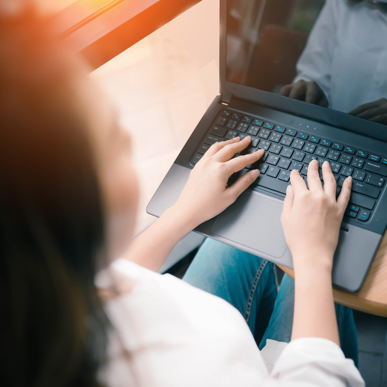 A woman using a laptop at a small desk