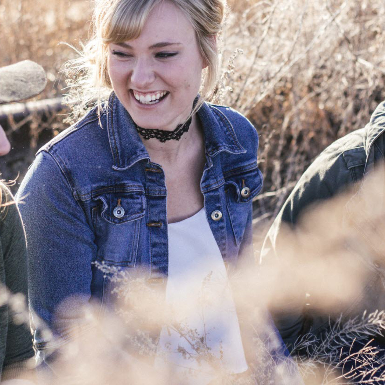 A group of young ladies laughing and sitting in a wheat field